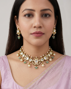 Woman wearing a traditional necklace and earrings with a pink saree against a neutral background