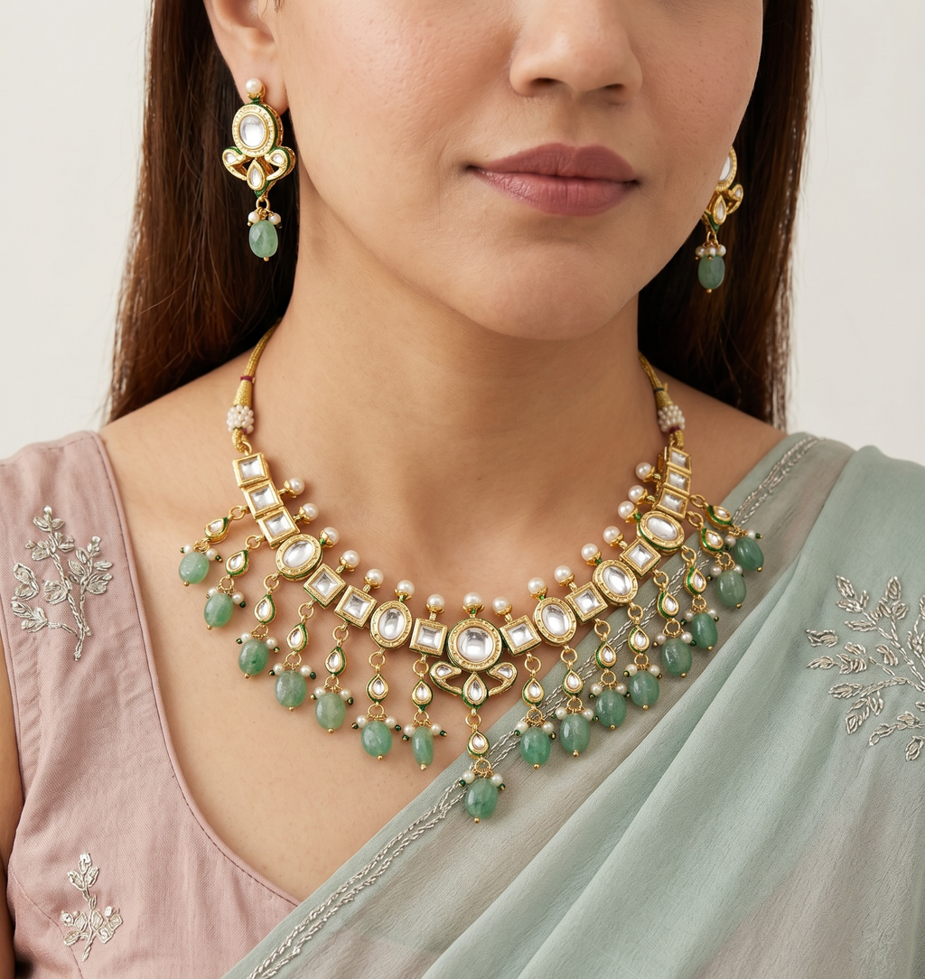 Woman wearing a gold and green necklace with matching earrings, against a neutral background.